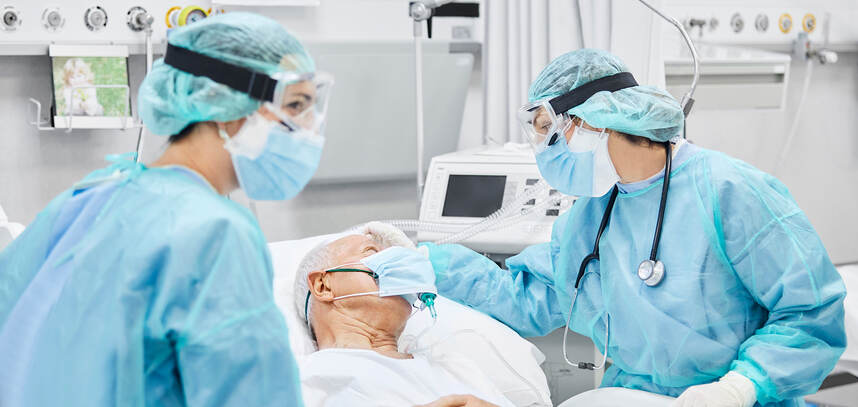 Medical professionals wearing personal protection equipment (PPE) attending to a hospital patient