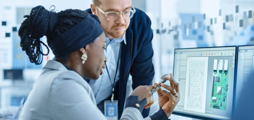 Colleagues discuss microchips in engineering workspace 