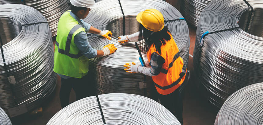People working with large spools of wire in a warehouse