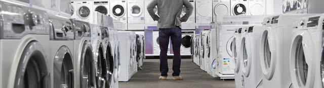 A person looking at many washers and dryers