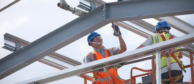 A construction worker laboring on a steel structure