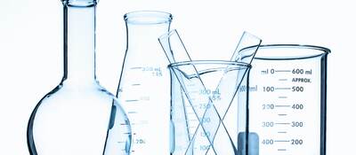 Glass beakers in front of a white wall