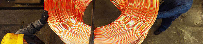 Workers moving roll of copper wire.