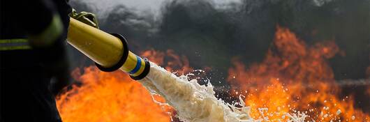 Firefighter spraying a fire with foam hose