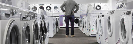 A person looking at many washers and dryers