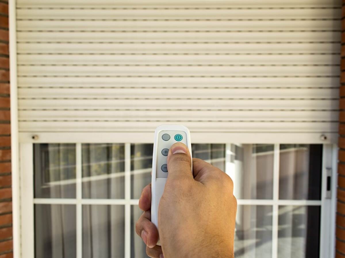 hand holding remote in front of a window