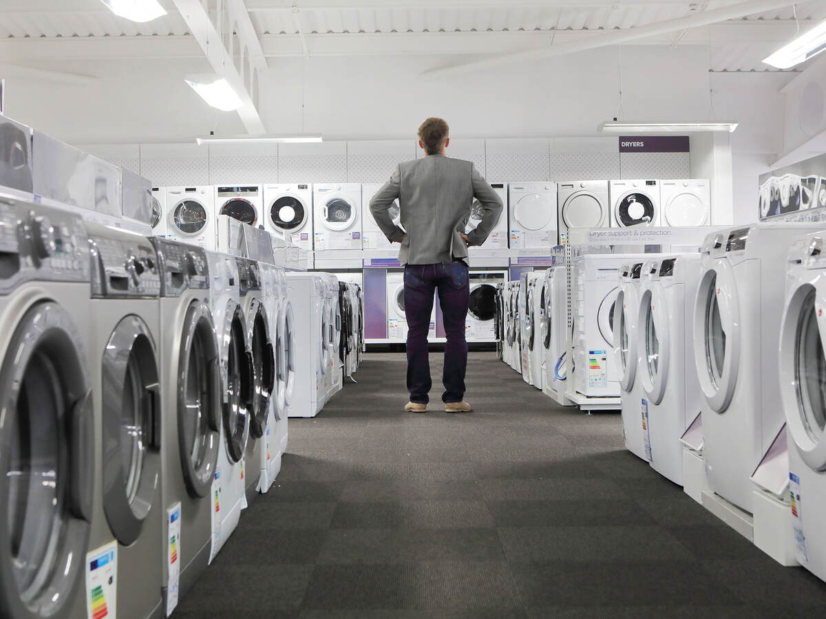 A person looking at many washers and dryers