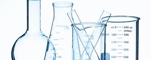 Glass beakers in front of a white wall